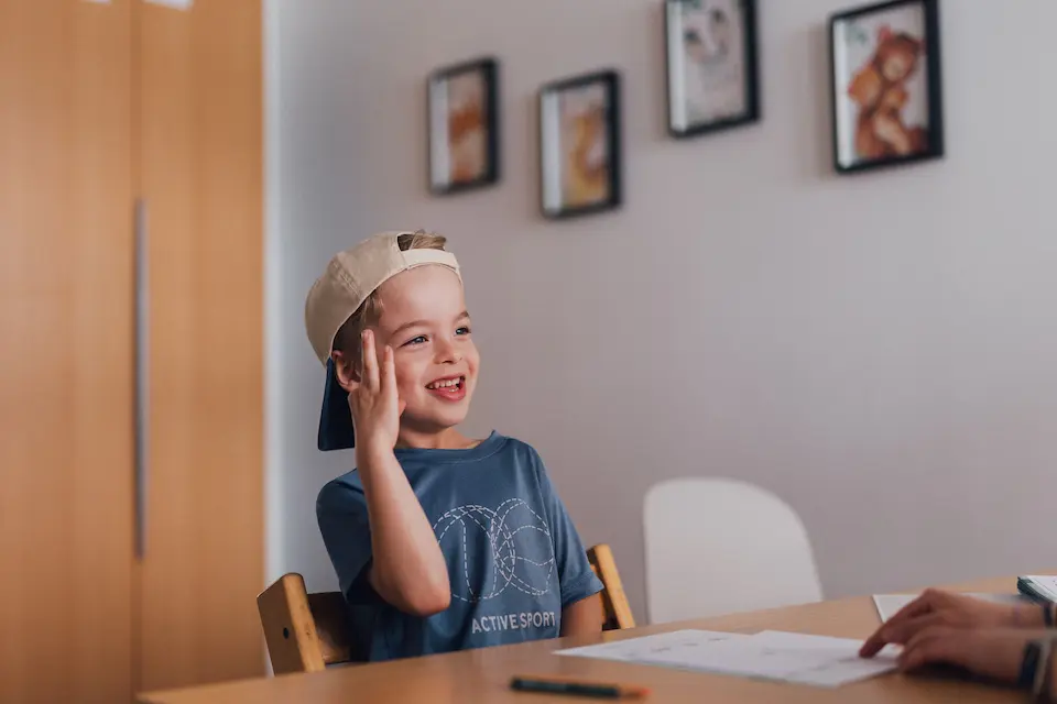 fröhliches Kind auf einem Stuhl in der Praxis Custers