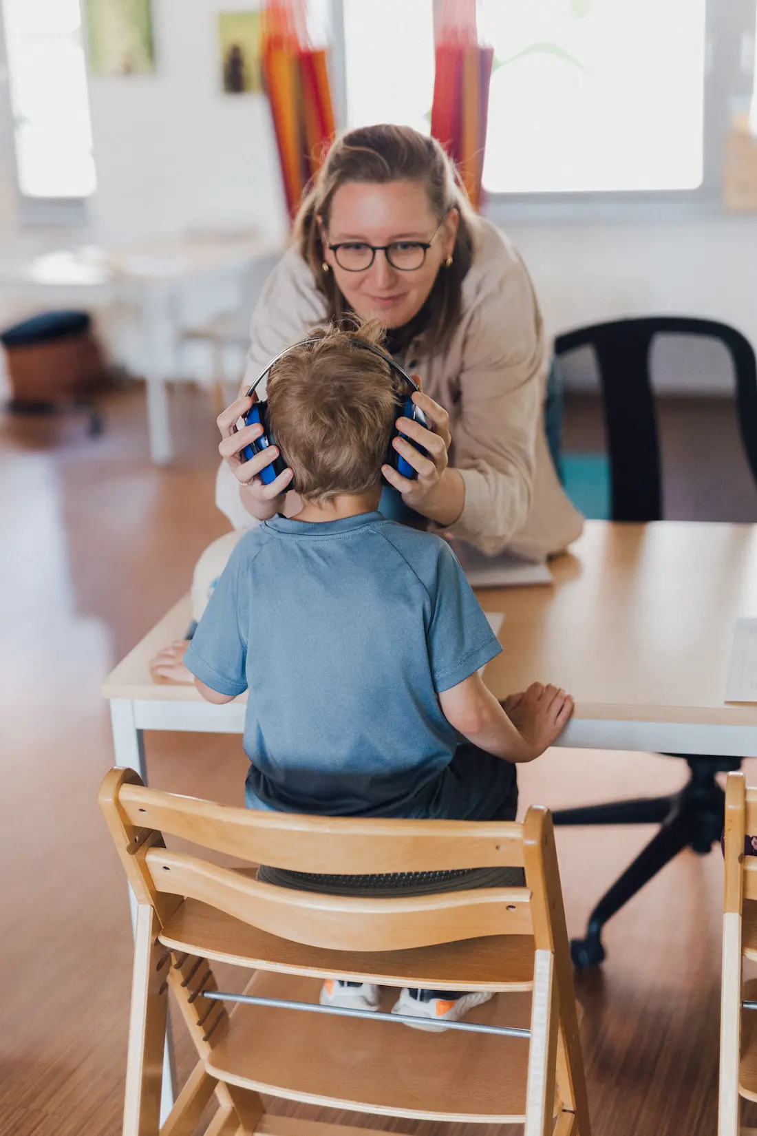 Ein Kind bekommt zur Ergotherapie Kopfhörer aufgesetzt
