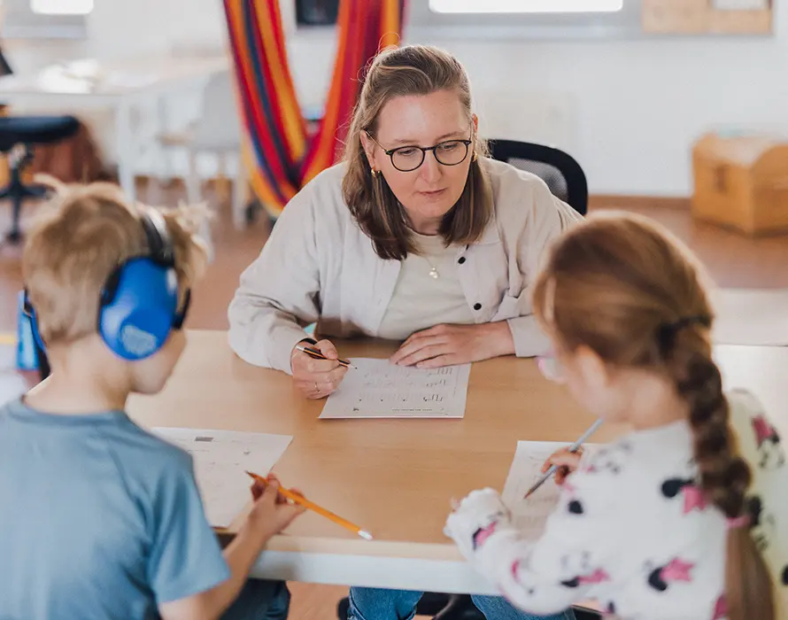 Zwei Kinder üben mit einer Ergotherapeutin