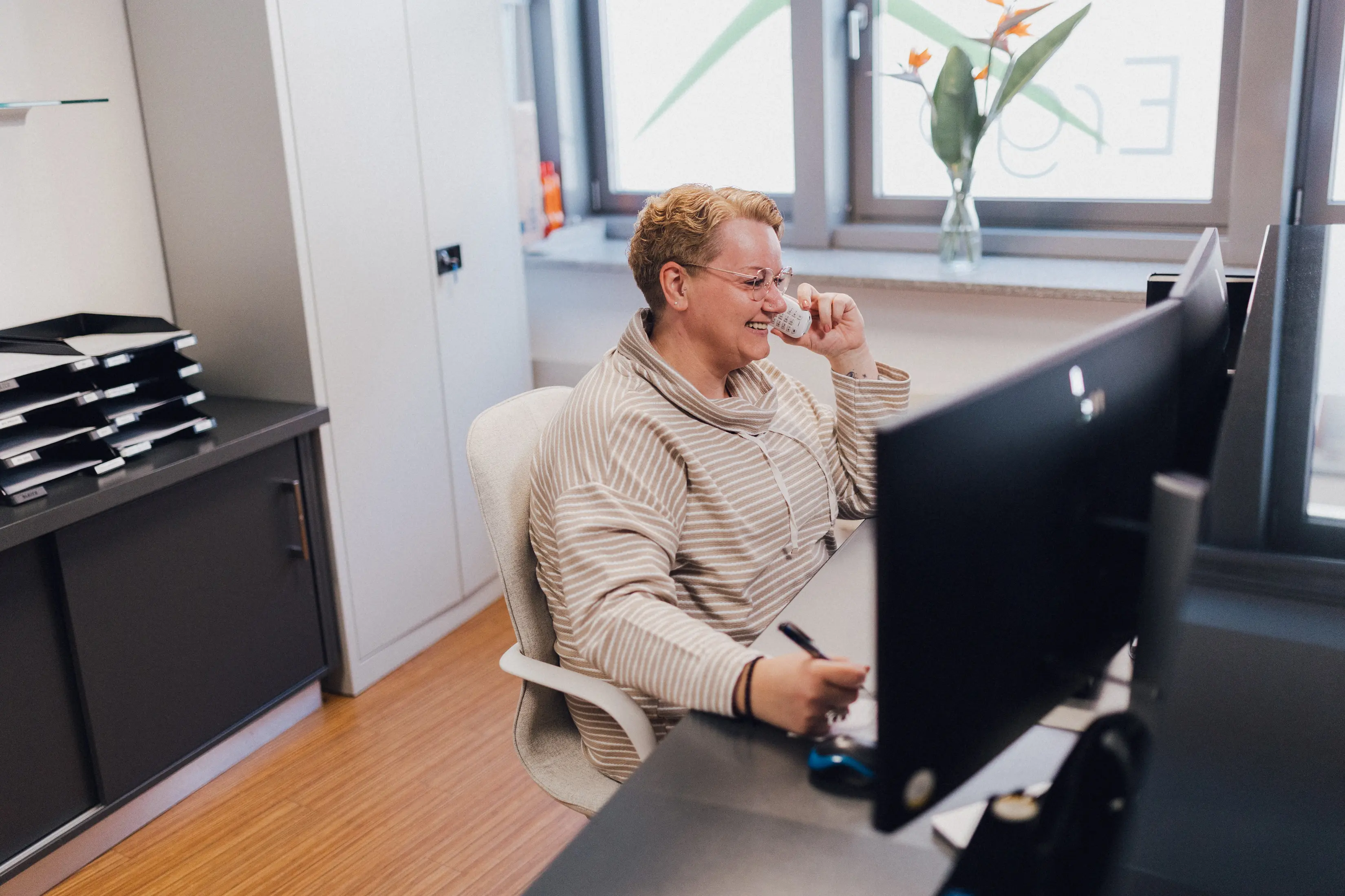 Sekretärin am Schreibtisch nimmt einen Anruf entgegen