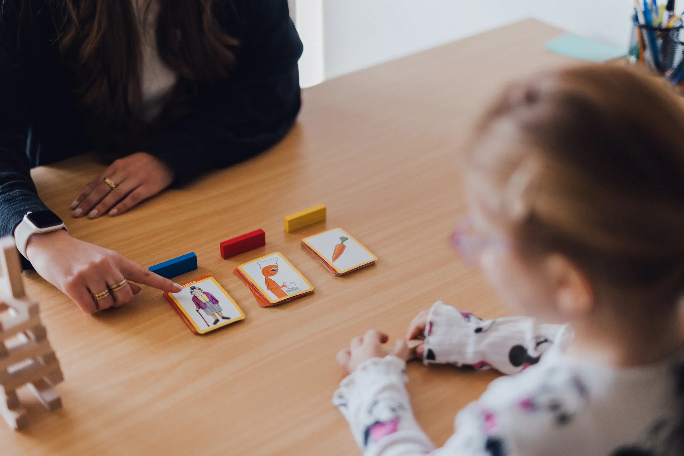 Bildkarten auf einem Tisch zwischen einem Kind und einer Logopädin