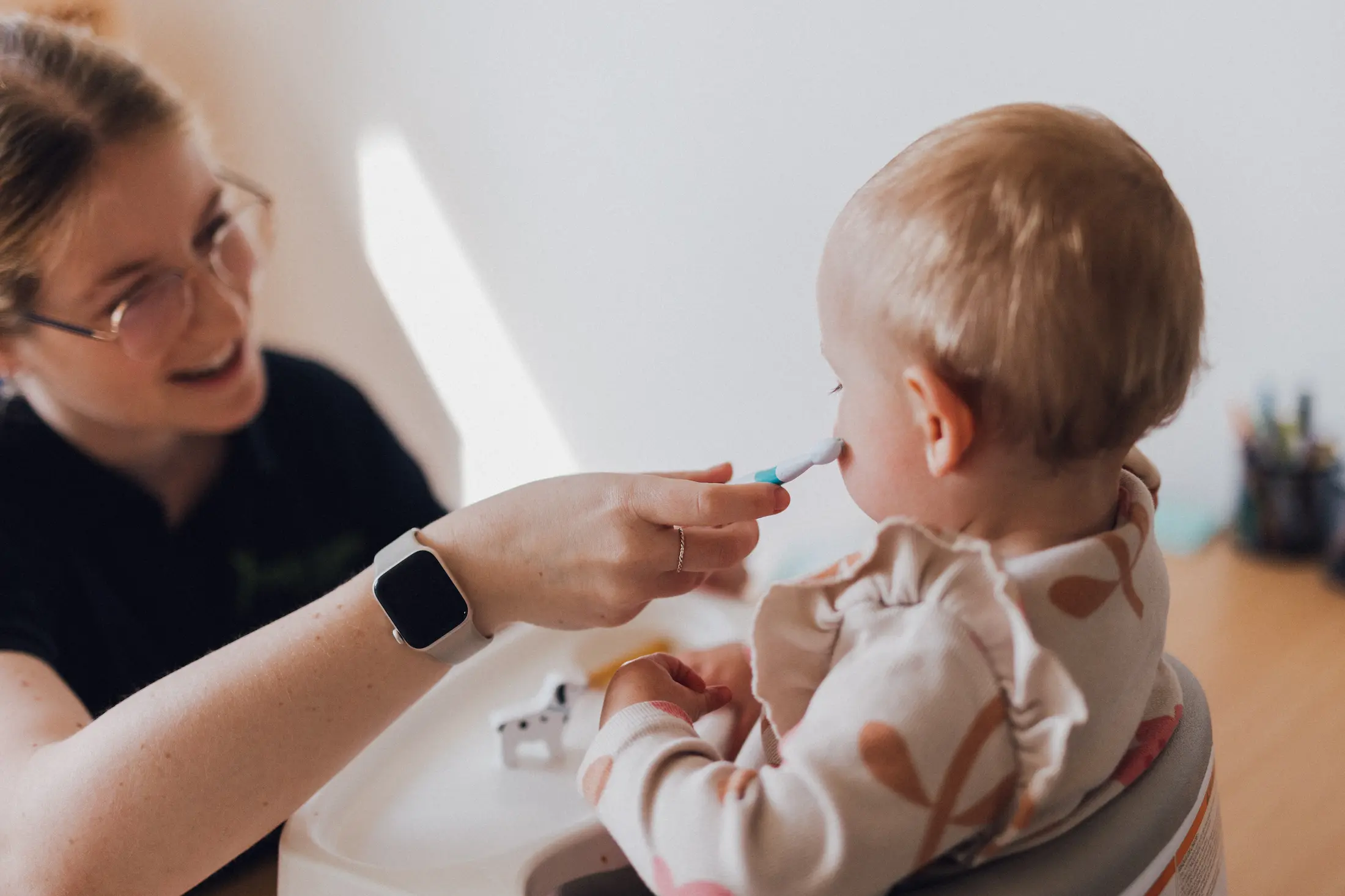 Logopädin füttert ein Baby in einem Hochstuhl