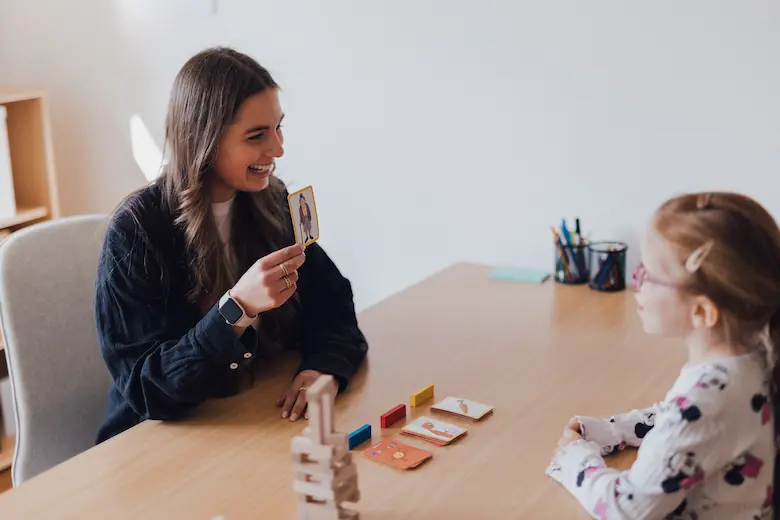 Logopädin übt mithilfe von Bildkarten mit einem Kind