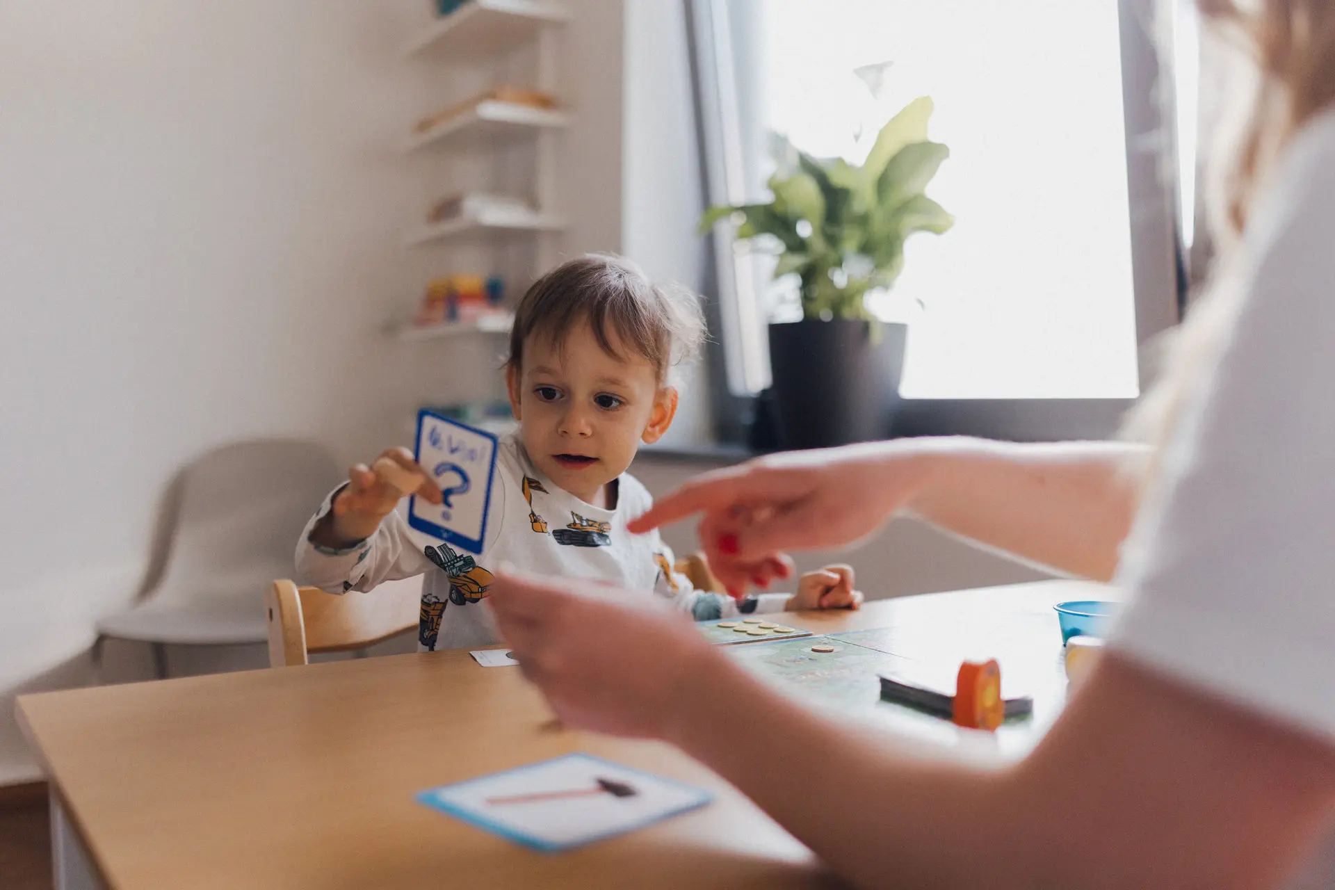 Kind spielt ein Brettspiel mit einer Logopädin